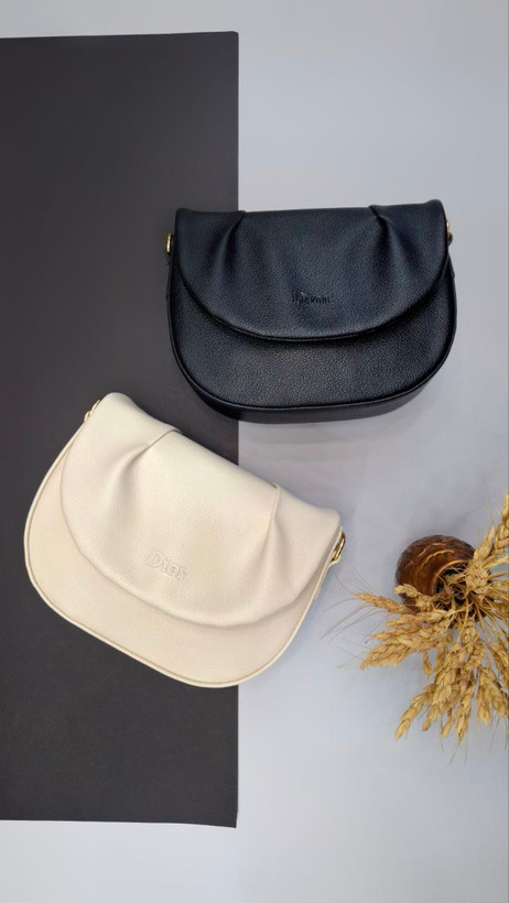 "کیف دوشی دخترانه و زنانه مدل دریسا با چرم مصنوعی، بند بلند مارکدار و طراحی نیمگرد."