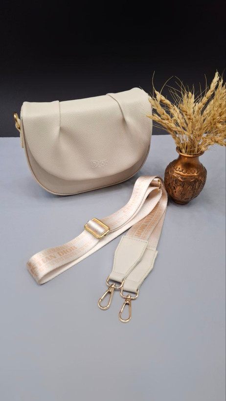 "کیف دوشی دخترانه و زنانه مدل دریسا با چرم مصنوعی، بند بلند مارکدار و طراحی نیمگرد."