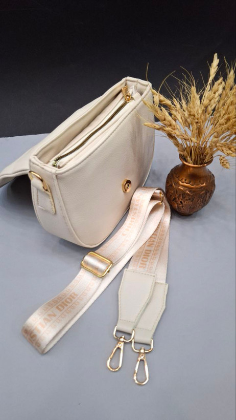 "کیف دوشی دخترانه و زنانه مدل دریسا با چرم مصنوعی، بند بلند مارکدار و طراحی نیمگرد."