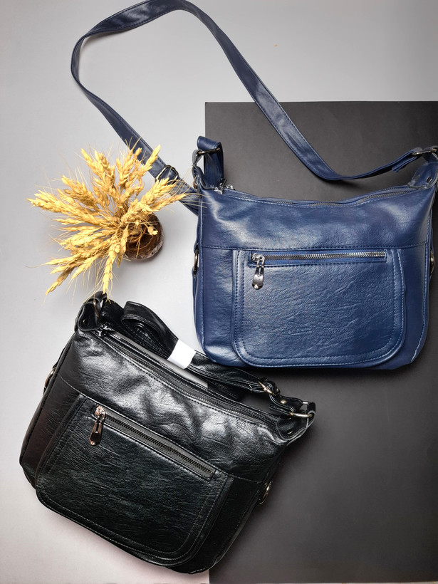 "کیف دوشی زنانه اوورا با طراحی ساده، چرم صنعتی شسته و زیپهای کاربردی، مناسب برای استفاده روزمره و اسپرت."